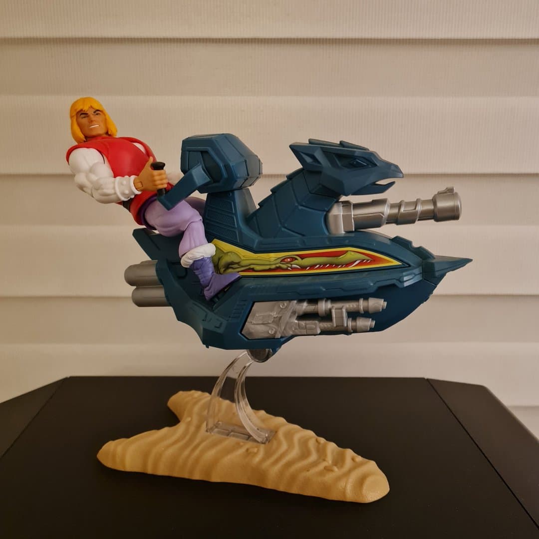 He-Man action figure on a blue vehicle with a sand-colored base.