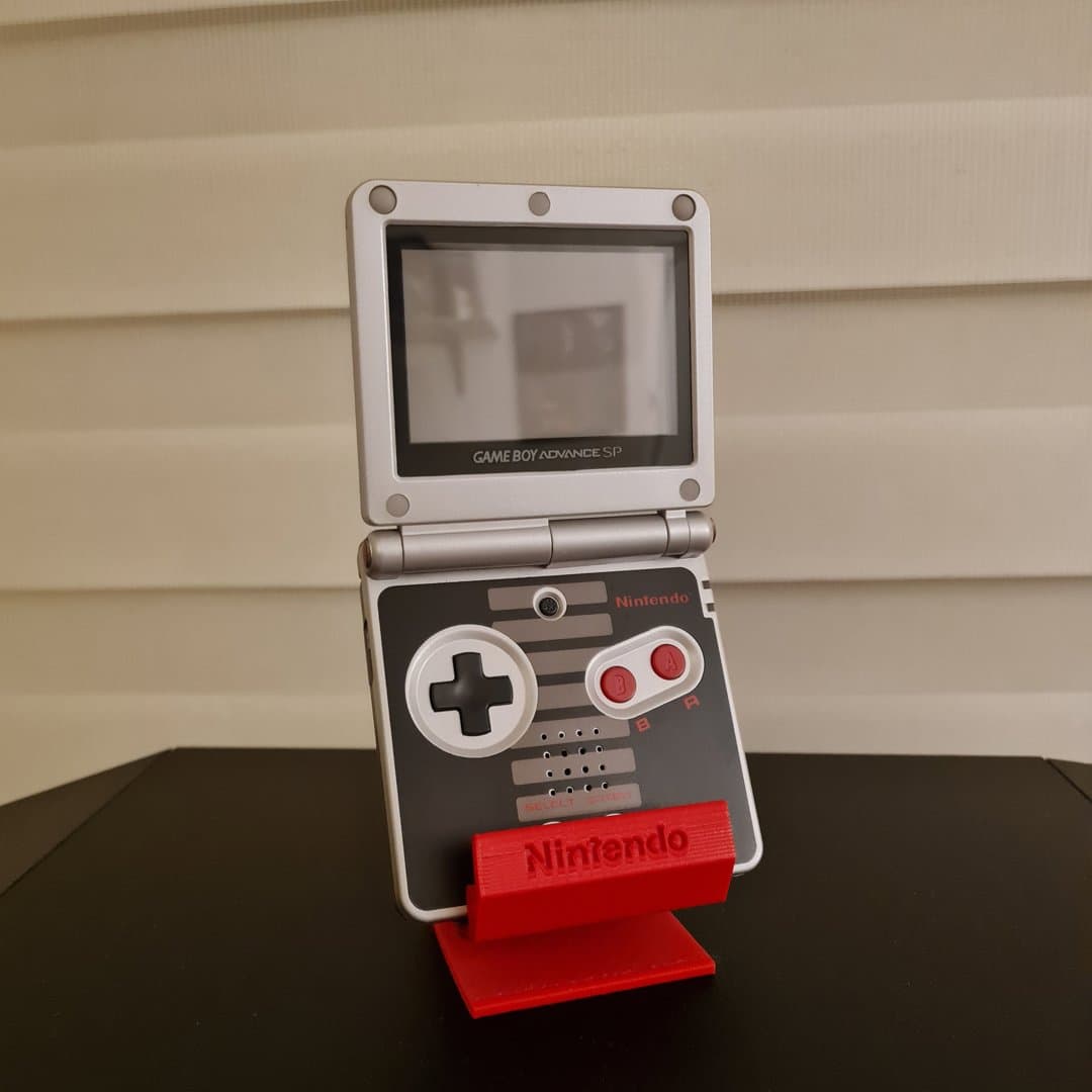 A silver Nintendo Game Boy Advance SP on a red stand.