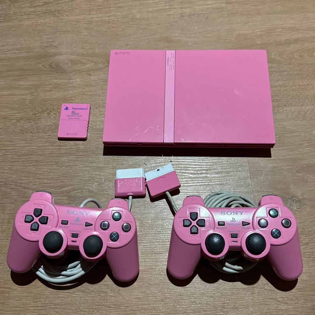 Pink Sony Playstation 2 console with controllers and memory card.