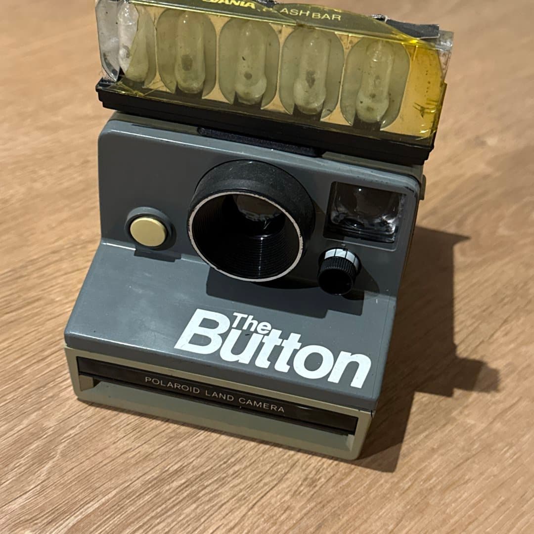 Vintage Polaroid "The Button" instant camera with flash bar.