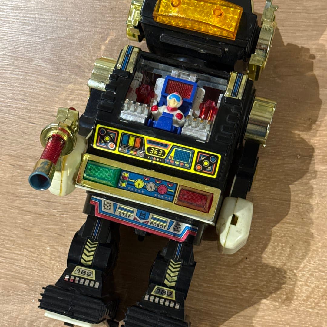 Vintage toy robot with a pilot inside, made of plastic and metal.