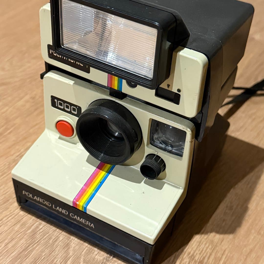 Vintage Polaroid Land Camera 1000, instant film camera with rainbow stripe.
