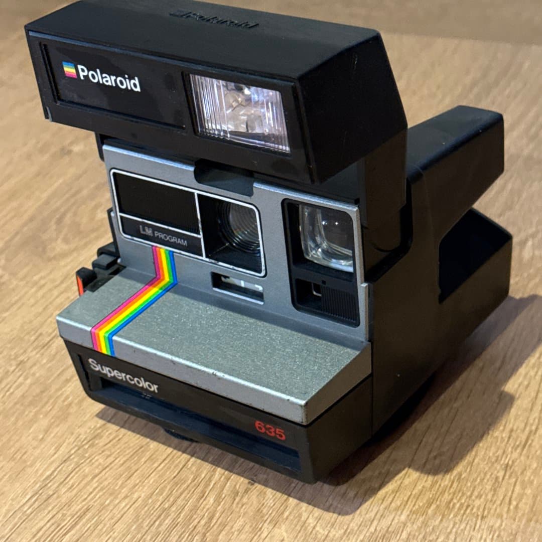 Vintage Polaroid Supercolor 635 instant camera with iconic rainbow stripe.