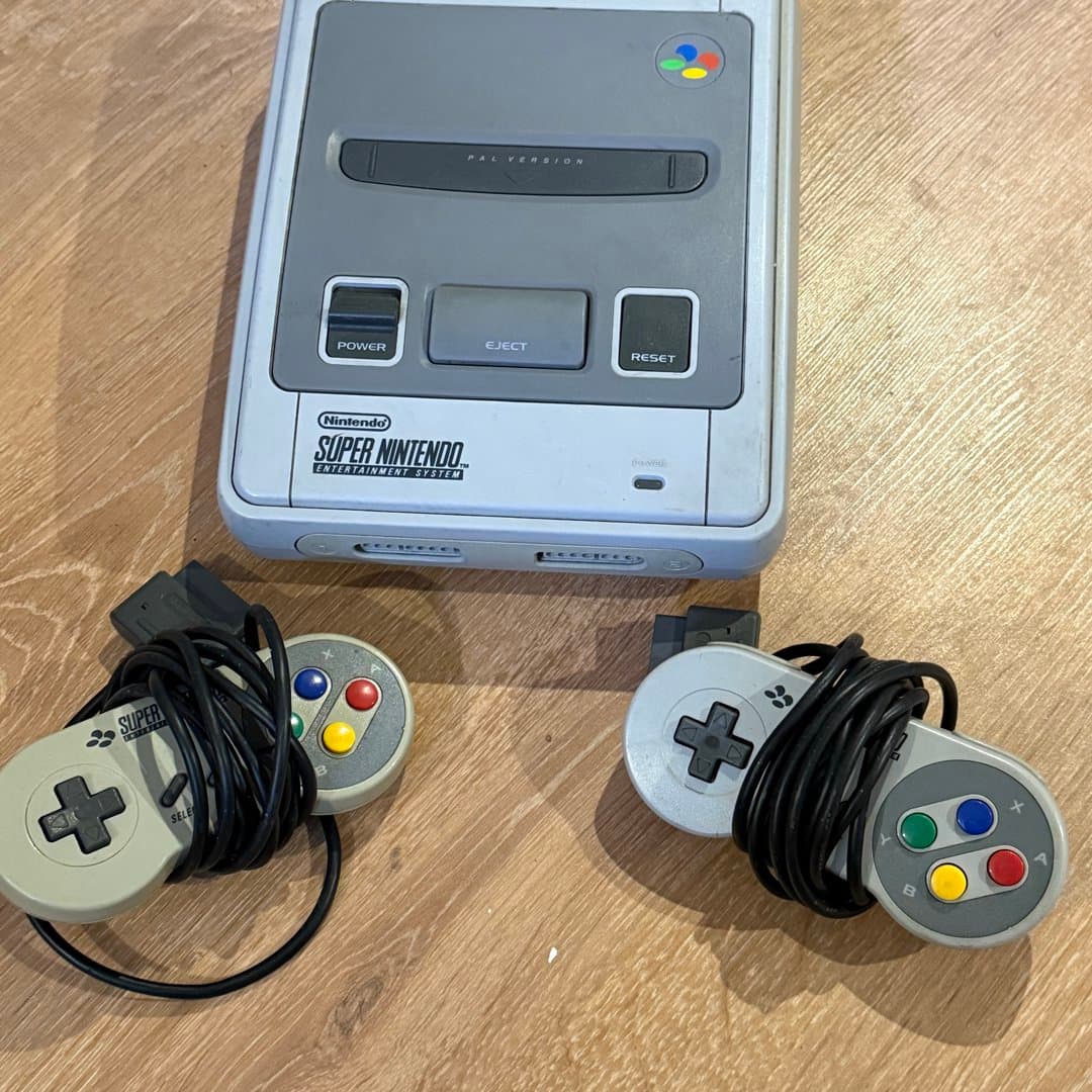 A vintage PAL Super Nintendo Entertainment System console with two classic controllers. - Photo 1