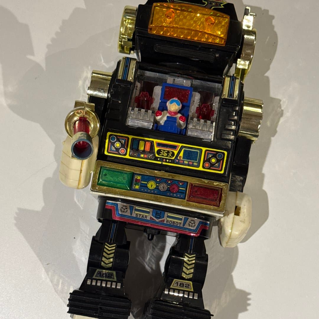 Vintage toy robot with a pilot inside, made of plastic and metal.