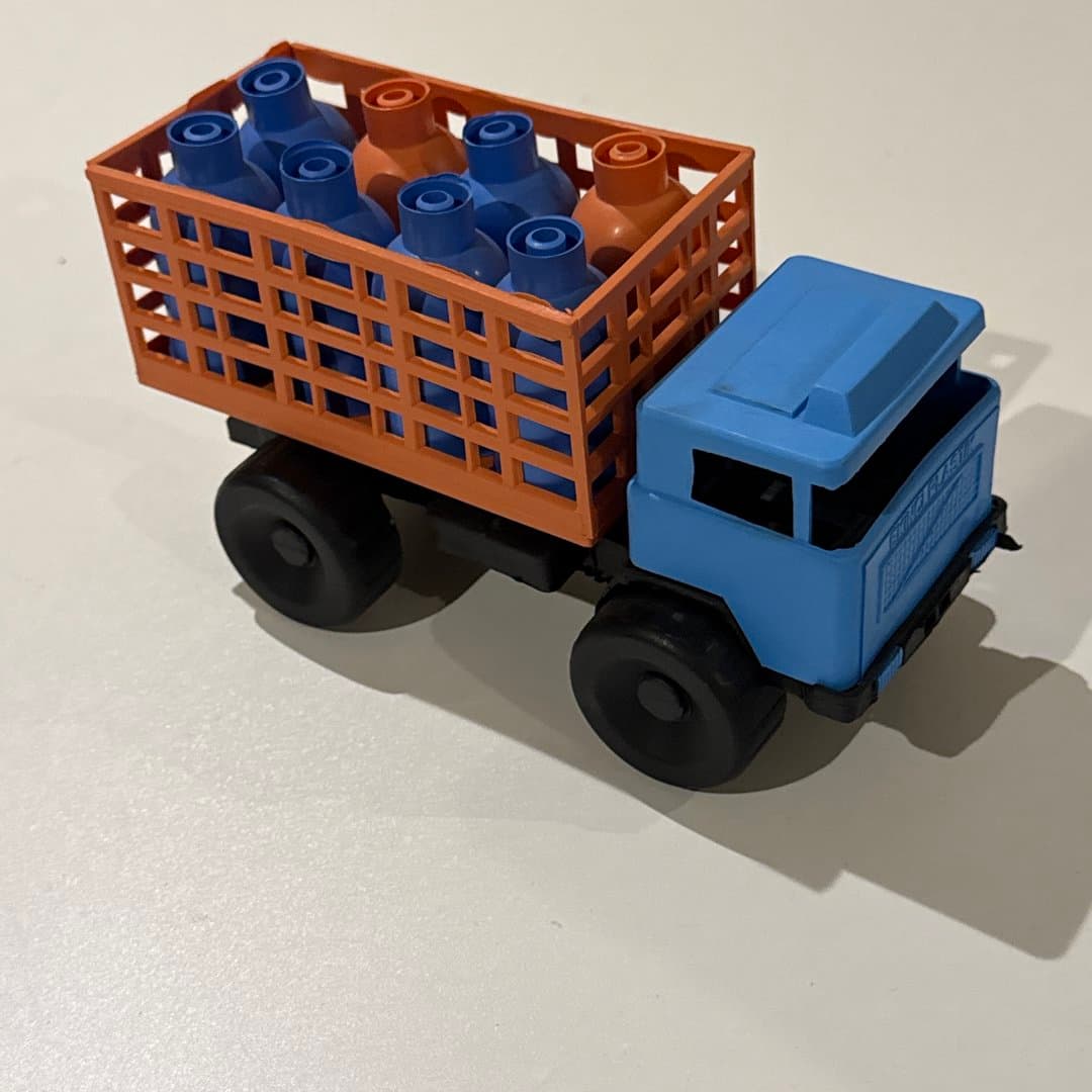 Colorful plastic toy truck carrying bottles in a crate, ideal for children's playtime.