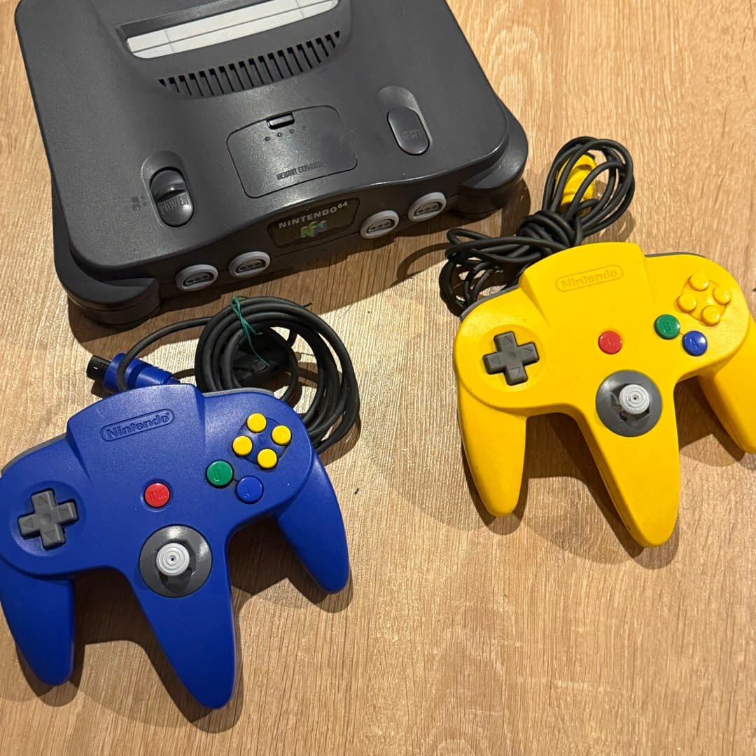 Classic Nintendo 64 console with two iconic N64 controllers (blue and yellow). - Photo 1