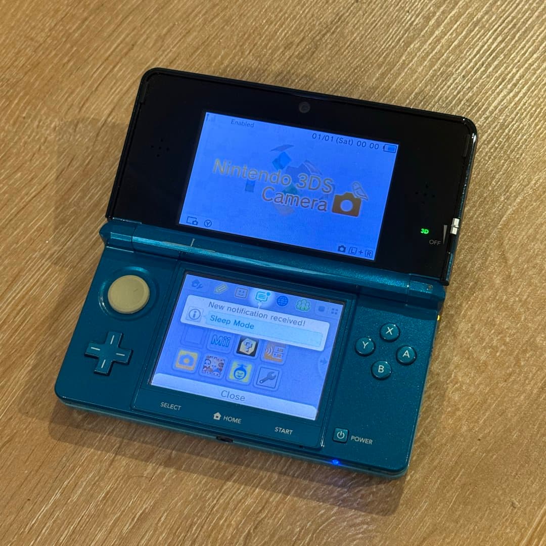 Blue Nintendo 3DS handheld console, showing the back with product information. - Photo 1