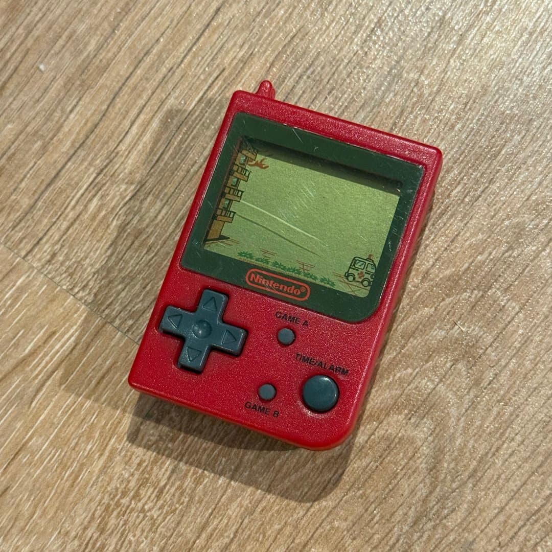 A vintage red Nintendo Game & Watch handheld electronic game, featuring the Fire game.