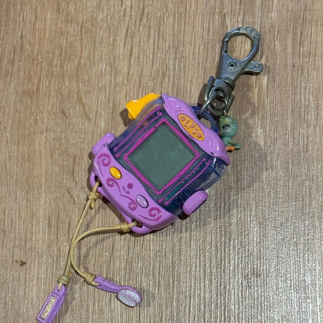 Retro purple Littlest Pet Shop virtual pet keychain with screen and mini brush accessory.