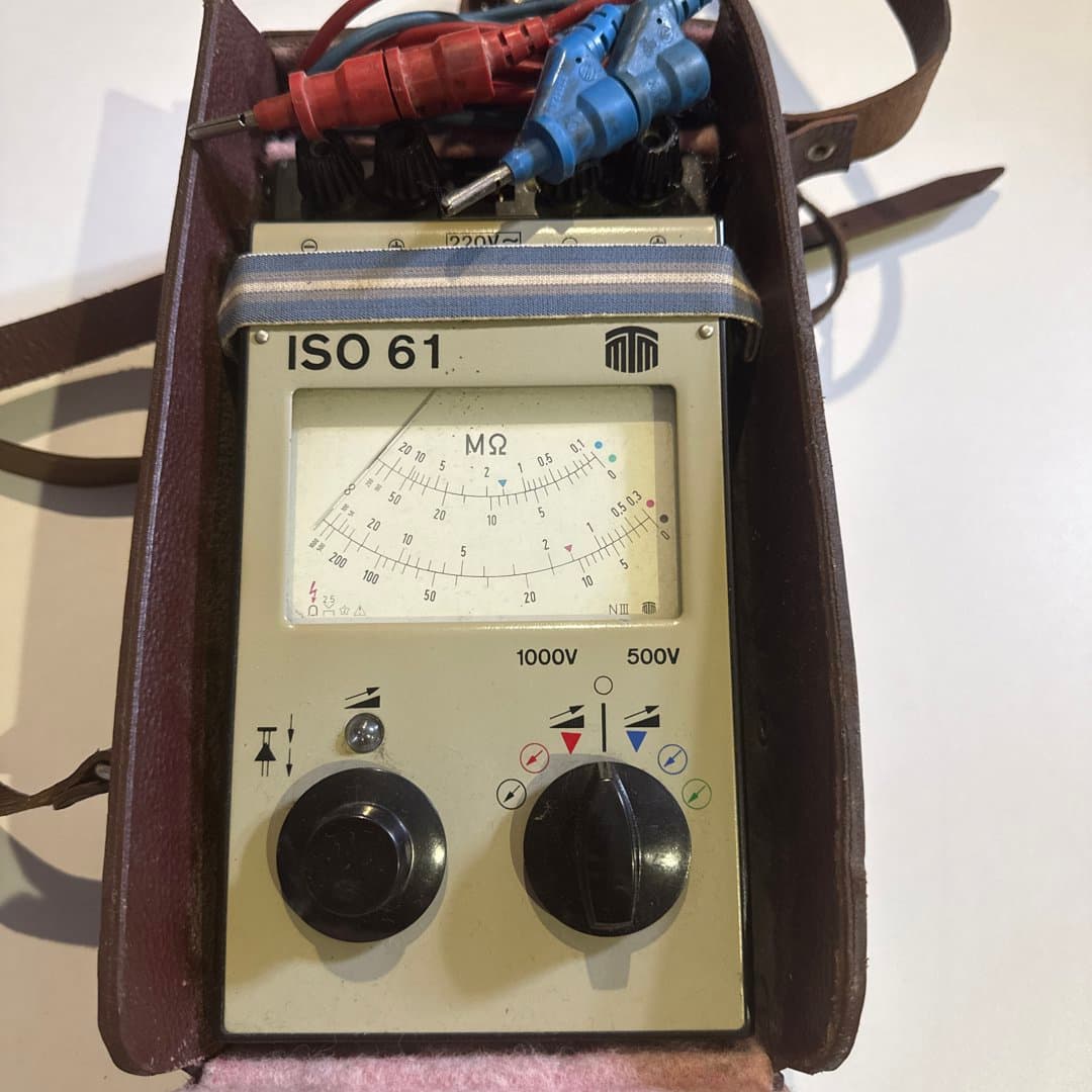 Vintage ISO 61 megohmmeter/insulation tester with probes in a leather case.