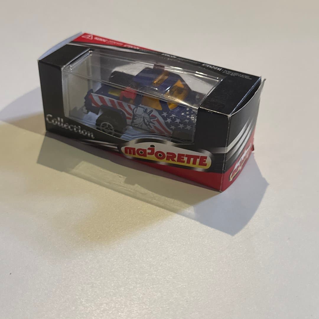 Majorette die-cast toy truck with patriotic American flag design in its collection box.