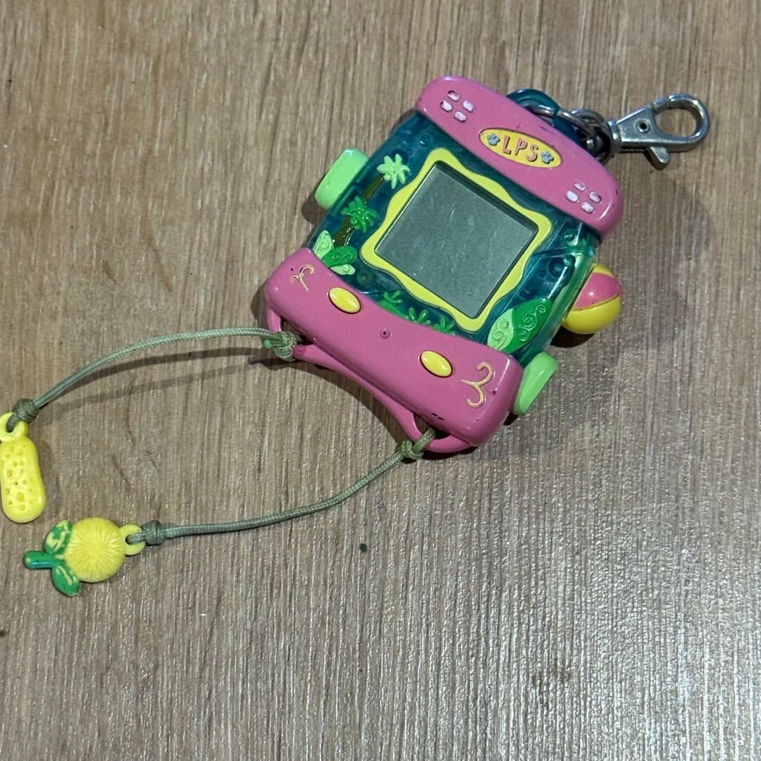 Pink and green Littlest Pet Shop virtual pet handheld game with screen and keychain.