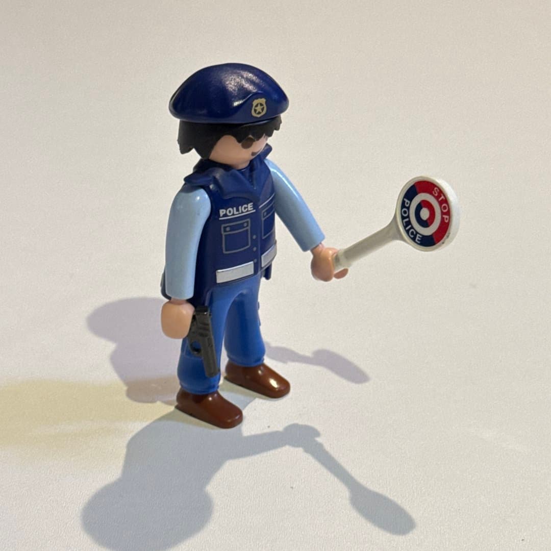 Playmobil Geobra police officer figure with stop sign, pistol, and beret.