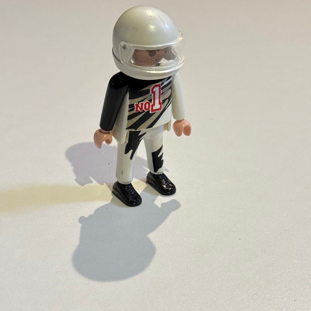 Playmobil race car driver toy figure wearing a white helmet and black/white suit with "No 1".