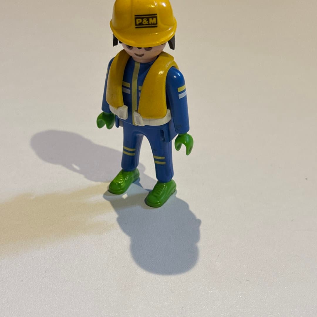 Playmobil-style Geobra 1992 worker figure in blue uniform, yellow safety vest & P&M hard hat.